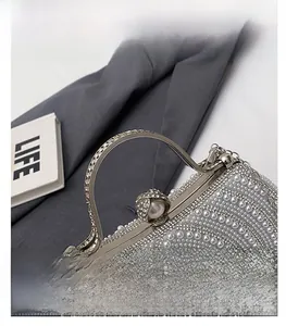 Detailed view of silver evening bag with pearls, rhinestones and curved metal handle