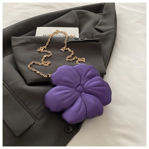Detail of purple flower-shaped acrylic bag with matte texture and gold chain strap