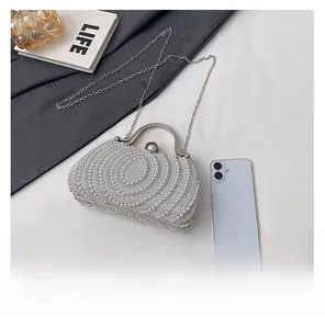 Detail of elegant pearl evening bag with silver handle next to a smartphone for scale