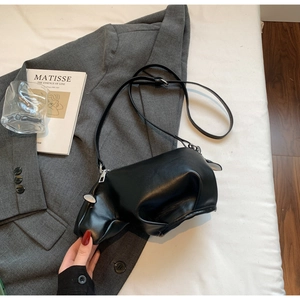 Vue détaillée d'un sac bandoulière hippopotame noir sur un blazer gris élégant