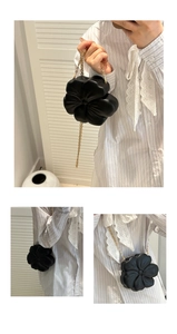 Detail of black 3D flower-shaped clutch with gold chain strap for luxury evening wear