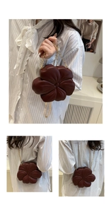 Detailed view of the dark brown flower-shaped handbag with a gold metal chain strap