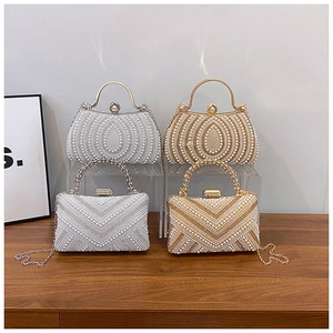 Detail of elegant pearl evening bags with vintage metal handles and gold chain straps