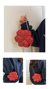 Detail of red flower-shaped acrylic clutch with matte finish and gold chain strap