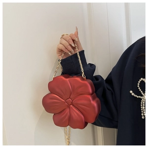 Detail of red 3D floral evening bag featuring matte petals and gold metal chain strap