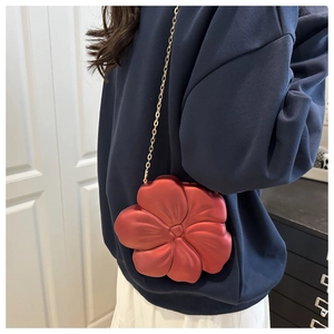 Detail view of a 3D red flower acrylic evening bag with an elegant gold chain strap