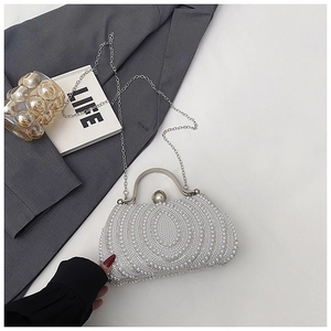 Detail of white pearl evening bag with silver metal handle and concentric pearl patterns