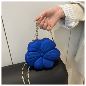 Detail of creative blue flower shaped clutch bag with golden metal chain strap