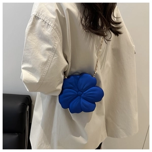 Detail of bright blue 3D flower acrylic clutch bag with delicate gold chain strap