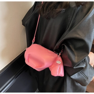 Détail du sac bandoulière rose en forme de vache porté avec une veste en cuir noir