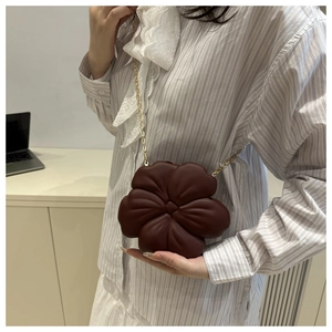 Detail of a dark red floral crossbody bag with 3D petals and a gold chain strap