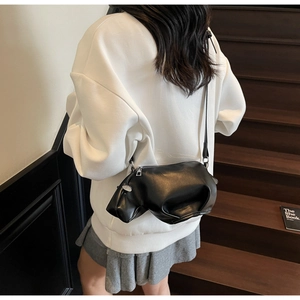 Détail du sac bandoulière en forme de vache en cuir noir lisse avec fermeture éclair en métal