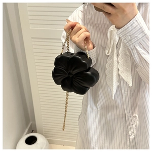 Detail view of the black 3D flower evening bag with elegant golden chain strap