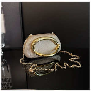 Detailed close-up of sparkling silver rhinestone evening bag with gold oval metal handle