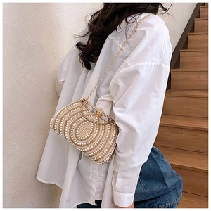 Detail of luxury pearl evening bag with gold chain worn over the shoulder by a model