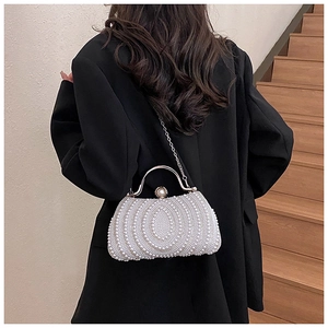Elegant pearl evening clutch bag with circular pattern and metal handle on a black suit