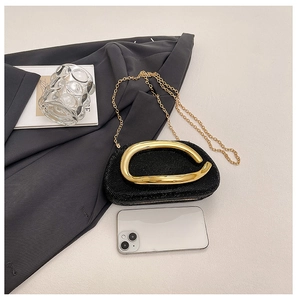 Detail view of a black rhinestone evening bag with gold metal handle and chain strap