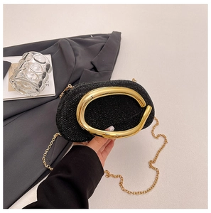 Detail of black rhinestone clutch with gold metal ring handle on charcoal blazer