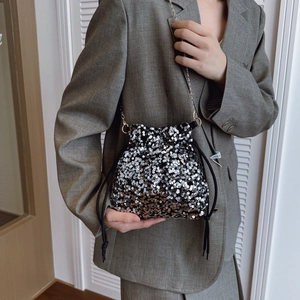 Chic silver and black sequin bucket bag with gold chain strap shown on a model