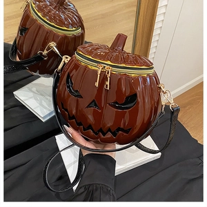 Detail of glossy Halloween pumpkin crossbody bag with face carving and gold hardware