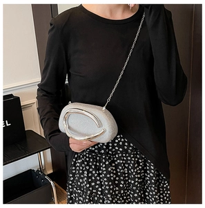Detail of silver rhinestone evening bag featuring a unique oval metal wrist handle