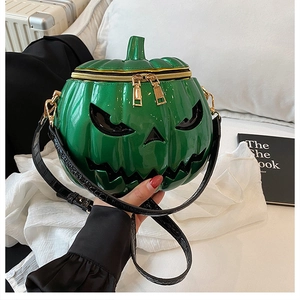 Detail of green pumpkin crossbody bag with glossy finish and golden dual zippers