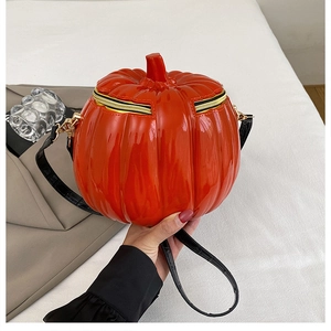 Detailed view of pumpkin-shaped crossbody bag with glossy orange finish and black strap
