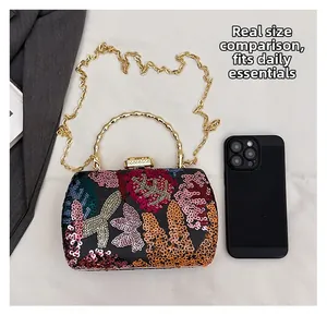 Detaillierter Größenvergleich einer Pailletten-Abendtasche neben einem Smartphone