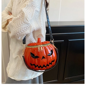 Close-up of orange pumpkin shoulder bag with black crocodile texture strap and gold hardware