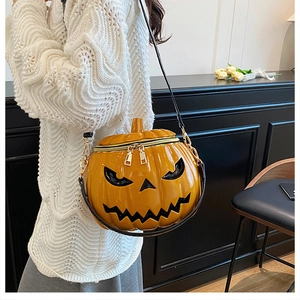 Detail of pumpkin-shaped crossbody bag with glossy orange finish and black face cutout