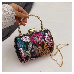 Detailed close-up of sequined evening clutch with bamboo-shaped metal handle and floral embroidery