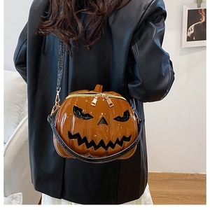 Detail of the glossy orange pumpkin shoulder bag with a Halloween face and gold zipper