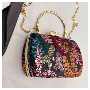 Close-up of evening bag featuring floral embroidery, sequins, and golden bamboo handle