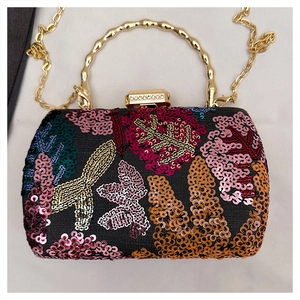 Detail of sequins embroidery on evening bag with gold bamboo handle and rhinestone clasp