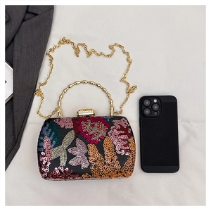 Macro shot of embroidered floral sequins and golden bamboo handle on a luxury evening bag