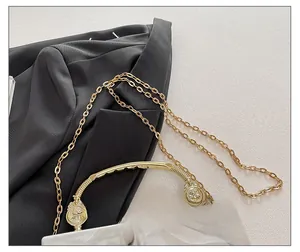Detail of white acrylic bag featuring gold chain strap and embossed portrait buckle