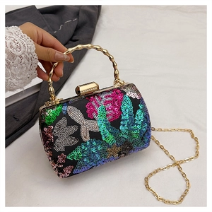 Close-up of colorful sequin embroidery and golden bamboo handle on an evening clutch bag