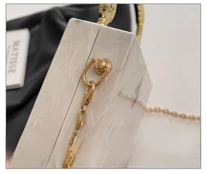 Close-up of premium gold hardware and marble texture on acrylic evening clutch bag
