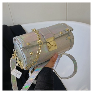 Détail de la texture crocodile holographique et rivets dorés sur un sac cylindre brillant