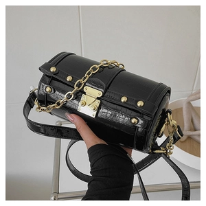 Détail du sac baril noir texture croco avec clous dorés et fermoir métallique