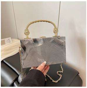 Detail of marble pattern acrylic clutch with golden metal handle and fine chain strap