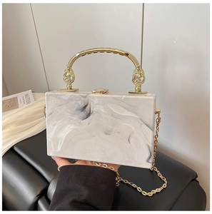 Detail of marble acrylic clutch with gold hardware handle and crossbody chain strap