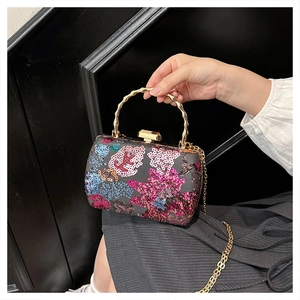 Detailed shot of sequin floral embroidery and golden bamboo handle on evening shell bag