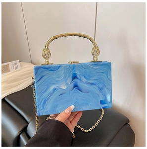 Detail of blue marble acrylic clutch with ornate gold handle and metal chain
