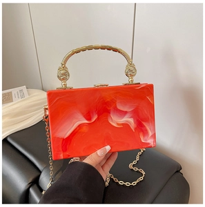 Detail of orange marble acrylic clutch bag with golden metal handle and chain strap