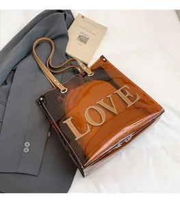 Detailansicht der braunen transparenten PVC-Tasche mit LOVE-Buchstaben-Patches und Innentasche