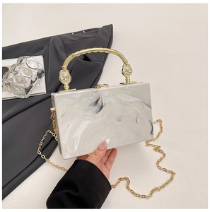 Detail of white marble acrylic evening bag with gold handle and metal chain strap