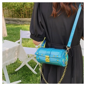 Détail du sac cylindre bleu aspect crocodile avec chaîne dorée et fini métallisé