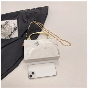 Macro shot of marble texture acrylic box bag with gold handle and size reference