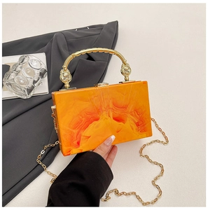 Detail view of the orange marble acrylic evening bag with golden spiral handle and chain